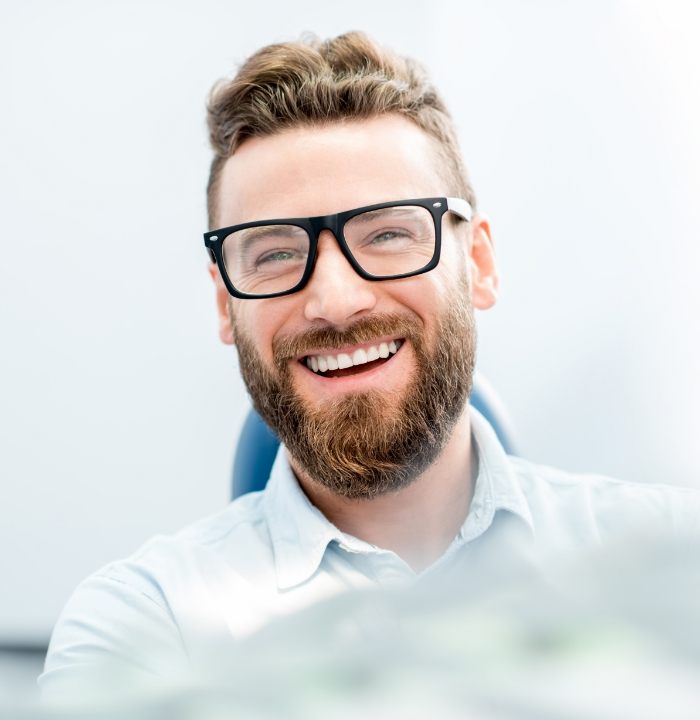 Man with beard and glasses grinning in dental chair
