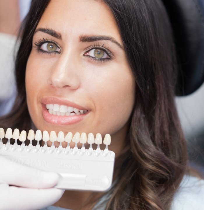 Woman in dental chair with row os veneers next to her smile