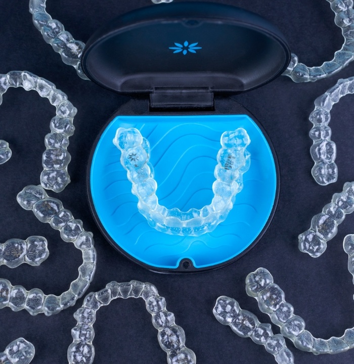 Several Invisalign clear aligners on table with one set in a case