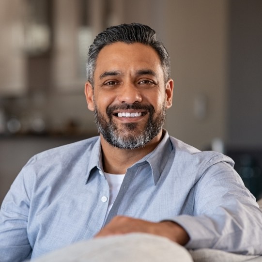 Man sitting on couch smiling after preventive dentistry visit