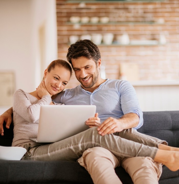 Man and woman looking at laptop while sitting on couch