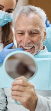 Senior dental patient looking at his smile in mirror