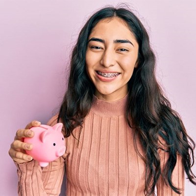 Girl with braces holding a piggy bank