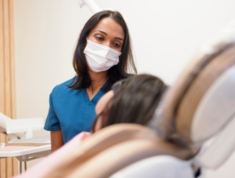 Dentist with clipboard sitting across desk from a patient