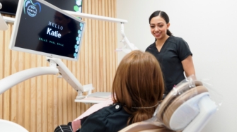 Young man in dental chair looking at his smile in a mirror