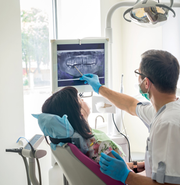 Dentist showing female patient X-ray of teeth