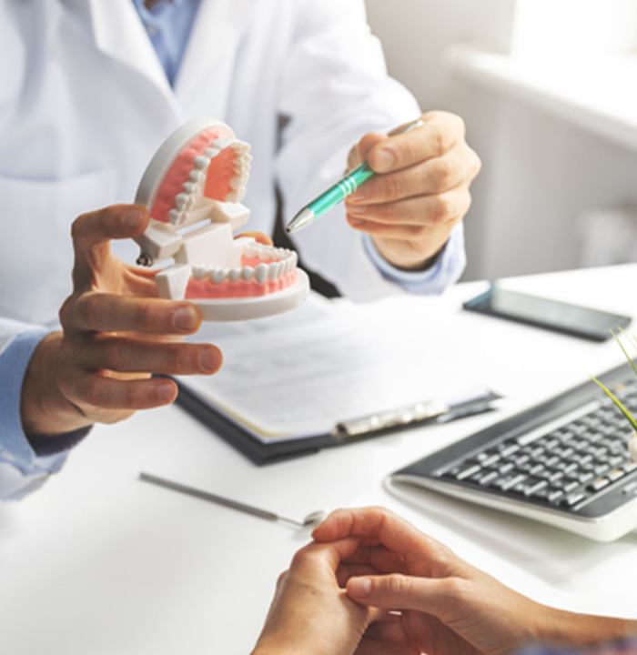 Dentist sitting at desk and showing patient dentures